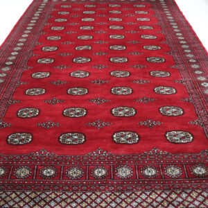 Handmade wool and cotton area rug or runner with repeated geometric Bokhara pattern displayed on floor