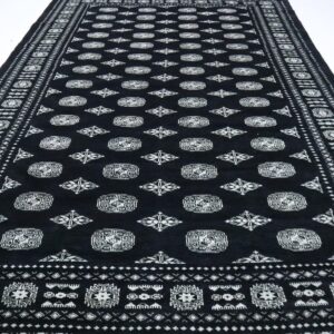 Handmade wool and cotton area rug or runner with repeated geometric Bokhara pattern displayed on floor