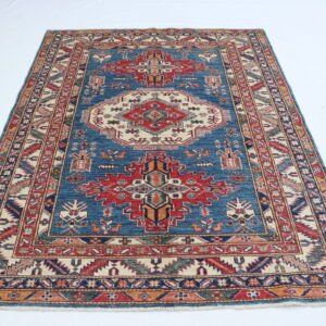 Handmade wool and cotton area rug or runner with traditional geometric Kazak pattern displayed on floor