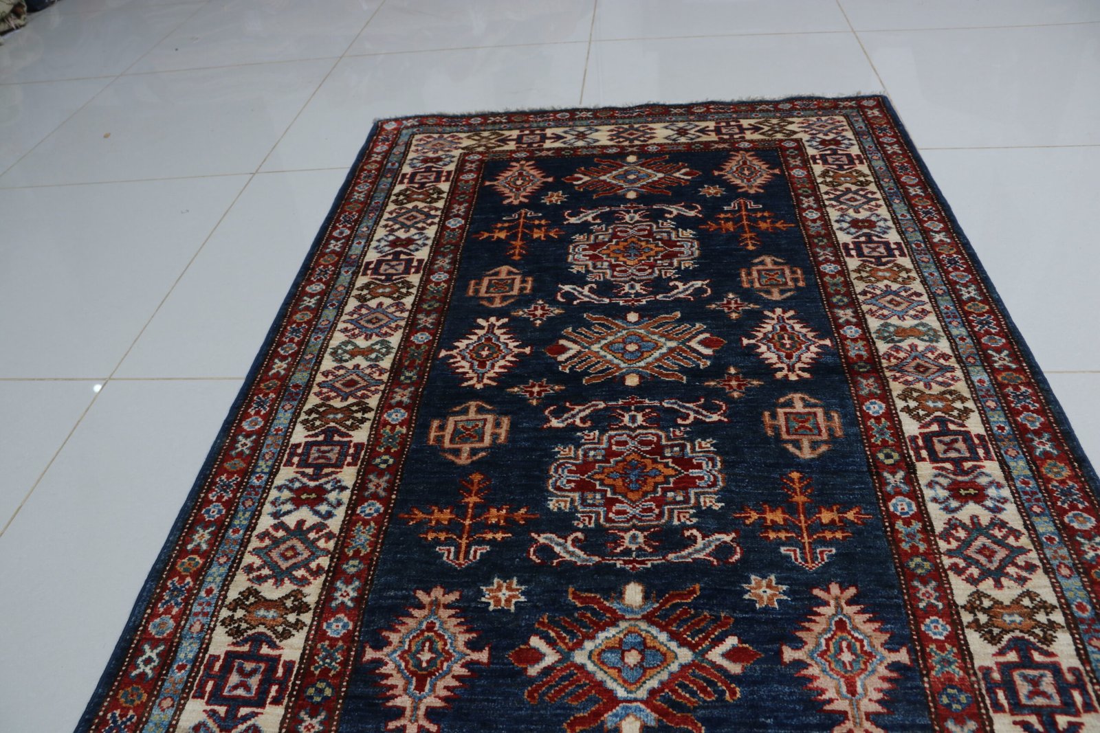 img 3874 Handmade wool and cotton area rug or runner with traditional geometric Kazak pattern displayed on floor