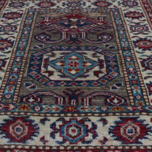 Handmade wool and cotton area rug or runner with traditional geometric Kazak pattern displayed on floor