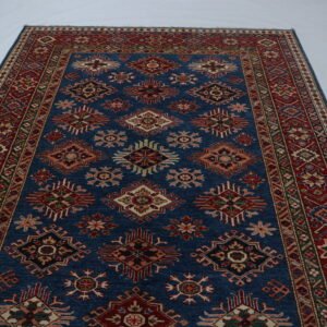 Handmade wool and cotton area rug or runner with traditional geometric Kazak pattern displayed on floor