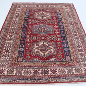 Handmade wool and cotton area rug or runner with traditional geometric Kazak pattern displayed on floorv