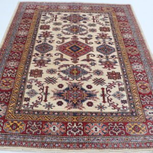 Handmade wool and cotton area rug or runner with traditional geometric Kazak pattern displayed on floor