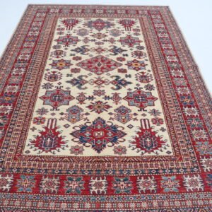 Handmade wool and cotton area rug or runner with traditional geometric Kazak pattern displayed on floor