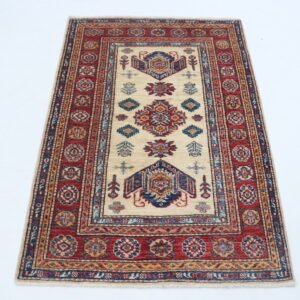 Handmade wool and cotton area rug or runner with traditional geometric Kazak pattern displayed on floor