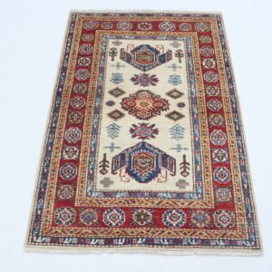 Handmade wool and cotton area rug or runner with traditional geometric Kazak pattern displayed on floor