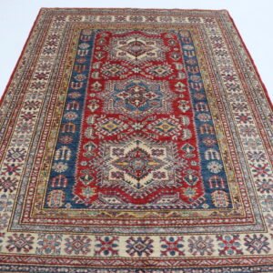 Handmade wool and cotton area rug or runner with traditional geometric Kazak pattern displayed on floor