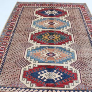 Handmade wool and cotton area rug or runner with traditional geometric Kazak pattern displayed on floor