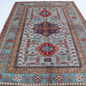 Handmade wool and cotton area rug or runner with traditional geometric Kazak pattern displayed on floor