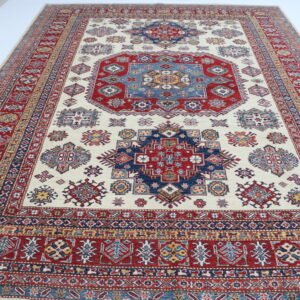 Handmade wool and cotton area rug or runner with traditional geometric Kazak pattern displayed on floor