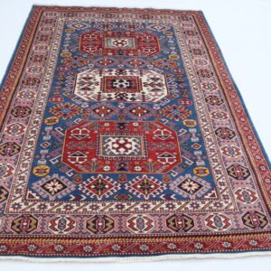Handmade wool and cotton area rug or runner with traditional geometric Kazak pattern displayed on floor