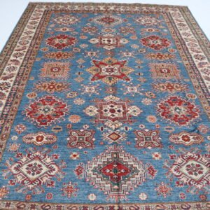 Handmade wool and cotton area rug or runner with traditional geometric Kazak pattern displayed on floor