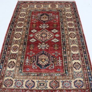 Handmade wool and cotton area rug or runner with traditional geometric Kazak pattern displayed on floor