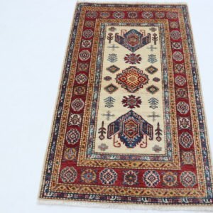 Handmade wool and cotton area rug or runner with traditional geometric Kazak pattern displayed on floor