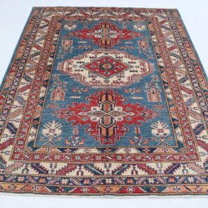 Handmade wool and cotton area rug or runner with traditional geometric Kazak pattern displayed on floor