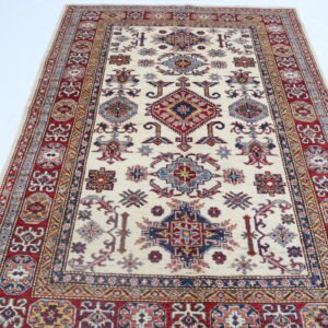 Handmade wool and cotton area rug or runner with traditional geometric Kazak pattern displayed on floor