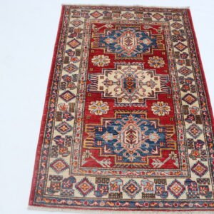 Handmade wool and cotton area rug or runner with traditional geometric Kazak pattern displayed on floor