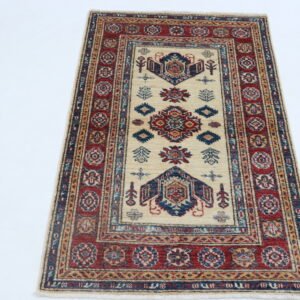 Handmade wool and cotton area rug or runner with traditional geometric Kazak pattern displayed on floor
