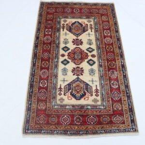 Handmade wool and cotton area rug or runner with traditional geometric Kazak pattern displayed on floor