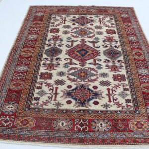 Handmade wool and cotton area rug or runner with traditional geometric Kazak pattern displayed on floor