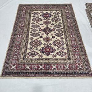Handmade wool and cotton area rug or runner with traditional geometric Kazak pattern displayed on floor