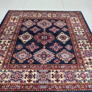 Handmade wool and cotton area rug or runner with traditional geometric Kazak pattern displayed on floor