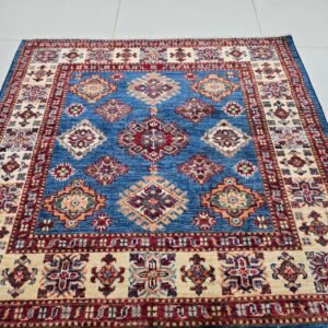 Handmade wool and cotton area rug or runner with traditional geometric Kazak pattern displayed on floor
