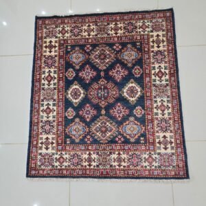 Handmade wool and cotton area rug or runner with traditional geometric Kazak pattern displayed on floor