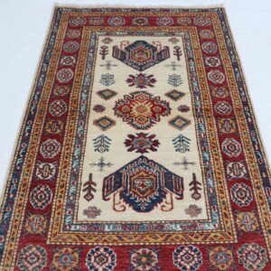Handmade wool and cotton area rug or runner with traditional geometric Kazak pattern displayed on floor