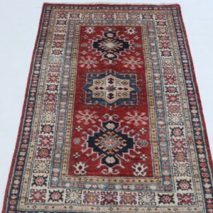 Handmade wool and cotton area rug or runner with traditional geometric Kazak pattern displayed on floor