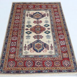 Handmade wool and cotton area rug or runner with traditional geometric Kazak pattern displayed on floor