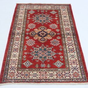 Handmade wool and cotton area rug or runner with traditional geometric Kazak pattern displayed on floor