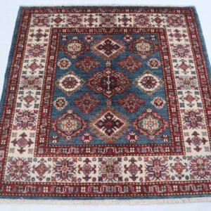 Handmade wool and cotton area rug or runner with traditional geometric Kazak pattern displayed on floor