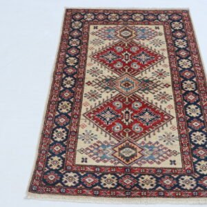 Handmade wool and cotton area rug or runner with traditional geometric Kazak pattern displayed on floor