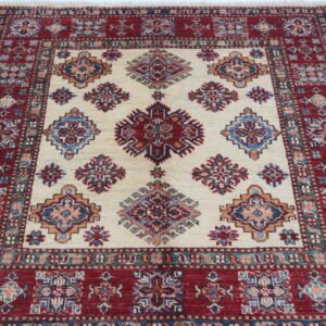 Handmade wool and cotton area rug or runner with traditional geometric Kazak pattern displayed on floor