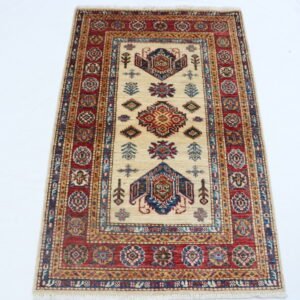 Handmade wool and cotton area rug or runner with traditional geometric Kazak pattern displayed on floor