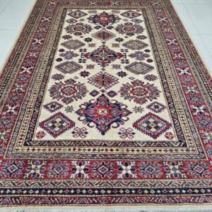 Handmade wool and cotton area rug or runner with traditional geometric Kazak pattern displayed on floor
