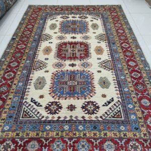 Handmade wool and cotton area rug or runner with traditional geometric Kazak pattern displayed on floor