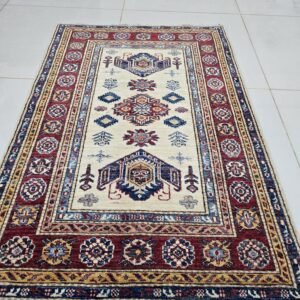 Handmade wool and cotton area rug or runner with traditional geometric Kazak pattern displayed on floor