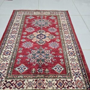 Handmade wool and cotton area rug or runner with traditional geometric Kazak pattern displayed on floor