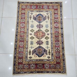 Handmade wool and cotton area rug or runner with traditional geometric Kazak pattern displayed on floor