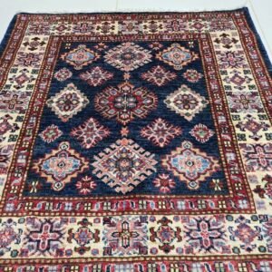 Handmade wool and cotton area rug or runner with traditional geometric Kazak pattern displayed on floor