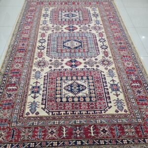 Handmade wool and cotton area rug or runner with traditional geometric Kazak pattern displayed on floor