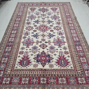 Handmade wool and cotton area rug or runner with traditional geometric Kazak pattern displayed on floor