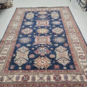 Handmade wool and cotton area rug or runner with traditional geometric Kazak pattern displayed on floor